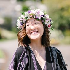 a woman wearing a flower crown on top of her head and smiling at the camera