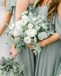 the bridesmaids are holding their bouquets with white flowers and greenery on them