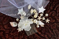 a hair comb with flowers and pearls on it sitting on a brown tableclothed surface