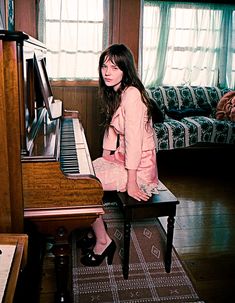 a woman sitting on top of a stool next to a piano