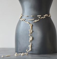 a white beaded belt on a mannequin with pearls attached to the waist