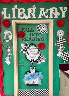 a green door decorated with paper flowers and writing on the front, surrounded by red tissue pom poms