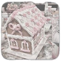 a gingerbread house decorated with pink icing and bows on the top, sitting on a table