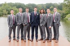 a group of men standing next to each other on top of a wooden pier near water