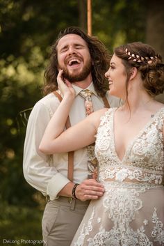 a bride and groom laughing together in the woods