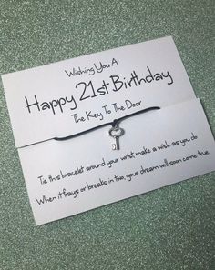 a happy 21st birthday card with a key to the door charm on it's back