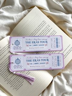 two bookmarks sitting on top of an open book with the words the eras tour