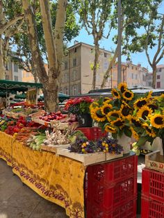 an outdoor market with sunflowers and other fruits and vegetables for sale on the table