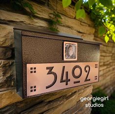 a close up of a house number plate on a stone wall with trees in the background