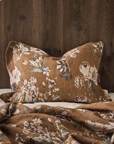 a bed with a brown floral comforter and pillows