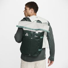 a man wearing a green and white backpack with his back turned to the camera,