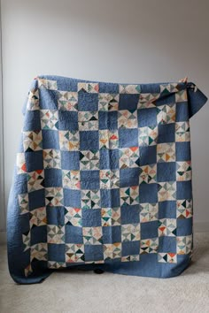 a blue and white quilt sitting on top of a floor next to a wall in a room