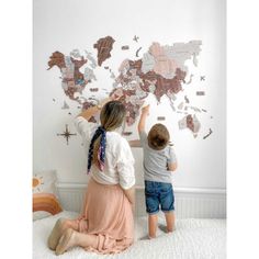 two children are playing with a world map on the wall