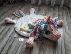 a crocheted unicorn laying on the floor next to a radiator with beads