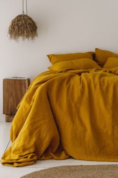 a bed with yellow sheets and pillows in a white room next to a brown rug