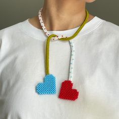 a woman wearing a beaded necklace with two hearts on it