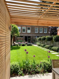 an open patio with wooden pergols and green grass