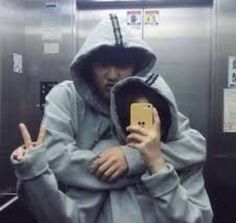 a person wearing a hoodie taking a selfie with their cell phone in an elevator