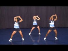 three women in blue shirts and black skirts are dancing on a stage with their hands behind their head