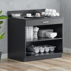 a black cabinet with plates and bowls on it next to a potted green plant