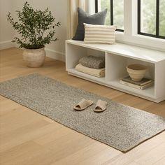 a living room with a rug, window and some shoes on the floor in front of it