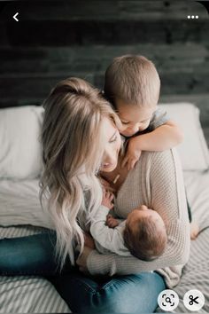 a woman holding a baby while laying on top of a bed