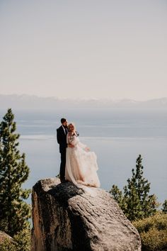 a bride and groom standing on top of a rock