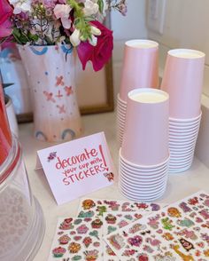 there are many pink vases and plates on the table with greeting cards in front of them