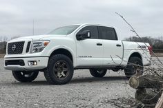 a white truck parked on top of a gravel field