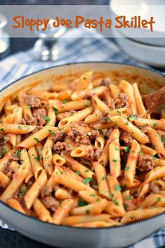 a pot filled with pasta and meat on top of a blue checkered table cloth