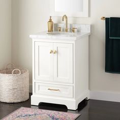 a white bathroom vanity with gold faucet, mirror and rug on the floor