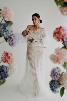 a woman in a white dress holding a baby