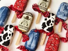 several popsicles decorated with cow prints and red ribbons