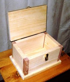 an open wooden box sitting on top of a table next to a wall with a curtain in the background