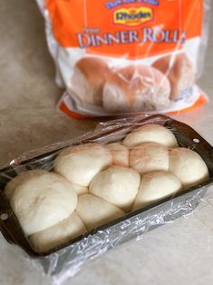 bread rolls are sitting on the counter next to a bag of dinner roll doughnuts