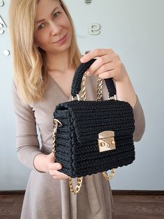 a woman holding a black crocheted purse