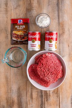 ingredients to make hamburger patties laid out on a wooden table next to a bowl of ground beef