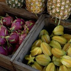 pineapples and dragon fruit in wooden boxes on display