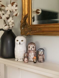 an owl figurine sitting on top of a mantle next to two other owls