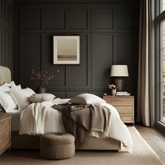 a bedroom with black walls and white linens on the bed, along with a footstool