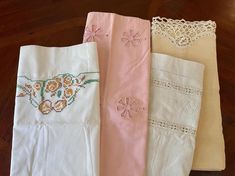 four pieces of white and pink linens on a wooden floor with lace trimming