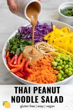 thai noodle salad with peanut sauce being drizzled over it in a white bowl