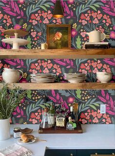 a kitchen with colorful wallpaper and shelves filled with plates, bowls, cups and utensils