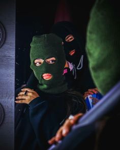 a woman wearing a green ski mask and looking at the camera