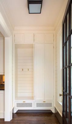 an empty room with white cabinets and wood floors