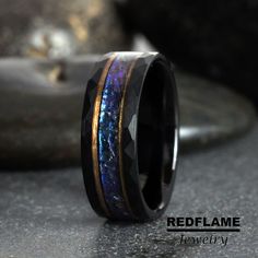 a ring with blue and gold inlays sitting on top of a gray surface