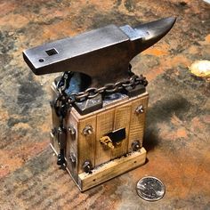 an old wooden box with a hammer and chain attached to it sitting on a table next to a penny