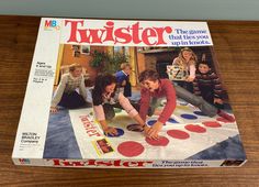 the magazine twister is sitting on top of a wooden table next to two children