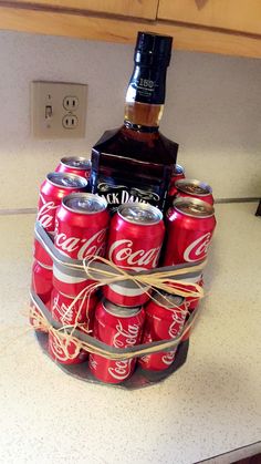 a stack of coca - cola cans sitting on top of a counter next to a bottle