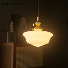 a light that is hanging from a ceiling in a dark room with the words lamp tasty above it